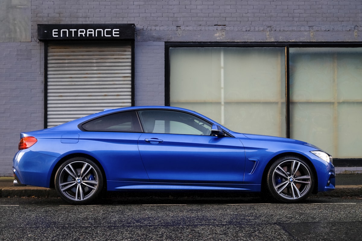 Blue BMW coupe parked outside a brick building